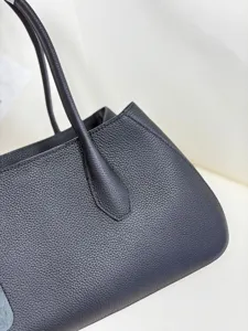 Detailed closeup of premium black genuine leather tote bag showing fine pebble texture.