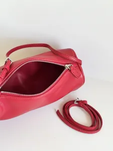 Sac cylindrique minimaliste en cuir rouge, sac bandoulière et porté épaule chic.