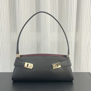 Detailed view of black leather shoulder bag with contrast burgundy lining and gold hardware.