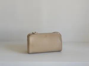 Vue détaillée du sac cylindrique en cuir beige minimaliste, mettant en valeur de fines coutures.