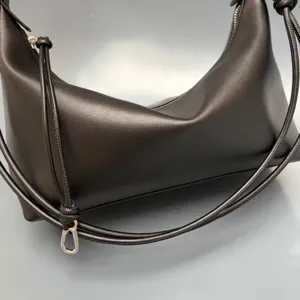 Black genuine leather shoulder bag minimalist croissant design with knotted drawstring strap detail.