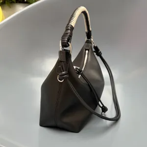 Detailed view of the black leather hobo bag featuring a chic woven handle and secure zipper.