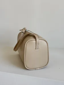 Détail en gros plan du sac à main cylindrique en cuir minimaliste avec sangle fine.
