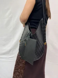 Detailed shot of black woven leather shoulder bag with matching pouch, stylish hobo design.