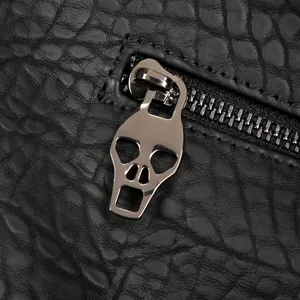 Primer plano detallado del tirador de cremallera con calavera y la textura de cuero negro.