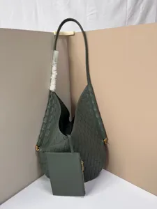 Closeup detail of dark green woven leather shoulder tote bag with small matching pouch.