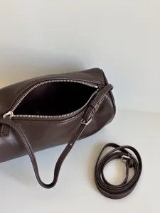 Gros-plan d'un sac cylindrique en cuir marron foncé minimaliste avec fermeture éclair.