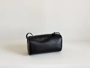 Sac cylindrique minimaliste en cuir noir, élégant sac bandoulière tendance pour femme.