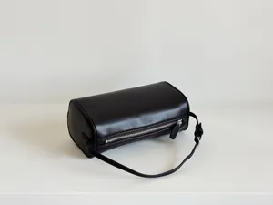 Détail de sac cylindre en cuir noir minimaliste, design chic bandoulière style 90s.