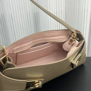 Detail view of taupe leather baguette shoulder bag with pink interior and gold hardware.