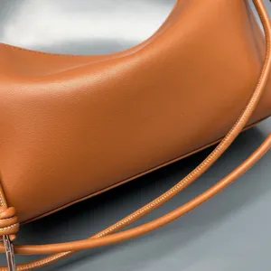 Close-up detail of luxury brown leather shoulder bag, highlighting fine grain texture and strap.