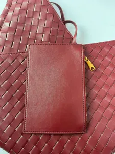 Detailed view of luxury burgundy woven leather tote bag with matching pouch for women.