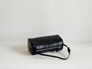 Détail de sac porté épaule cylindrique en cuir noir, sac oreiller minimaliste style années 90.