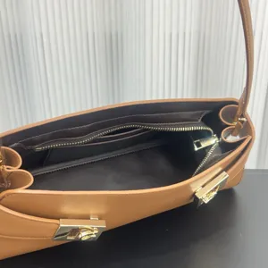 Elegant brown leather underarm shoulder bag with luxury gold hardware clasp and secure zip.
