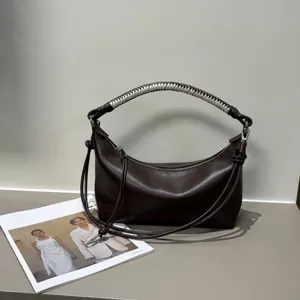 Detailed view of luxury dark brown leather shoulder bag with unique handmade woven handle design.