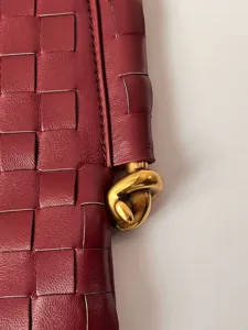 Burgundy woven leather handbag close up, soft texture shoulder bag detail showcase.