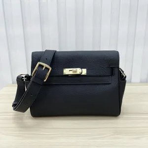 Close-up detail of the black leather crossbody bag featuring a golden metal lock closure.