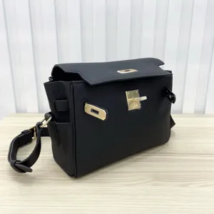 Detailed view of black genuine leather messenger bag with gold turn-lock hardware and strap.