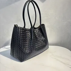 Close-up detail of black woven leather tote bag showing exquisite craftsmanship and texture.