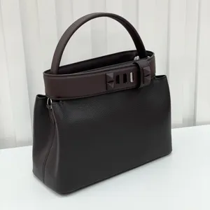 Elegant dark brown leather top handle handbag featuring a chic pyramid stud belt design.