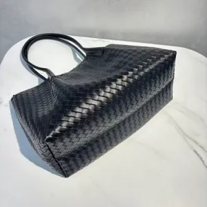 Black leather woven tote bag detail showing craftsmanship and large capacity design.