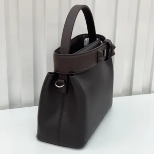 Dark brown leather handbag detail showing classic pyramid stud strap and structured design.