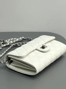 White quilted leather crossbody bag detail featuring classic silver chain and metal turn-lock.