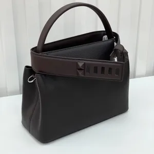 Dark brown top layer leather top handle bag with iconic pyramid stud detail and structured shape.