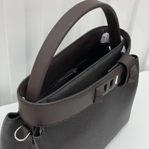 Detail view of brown leather top handle shoulder bag with metal hardware and texture.