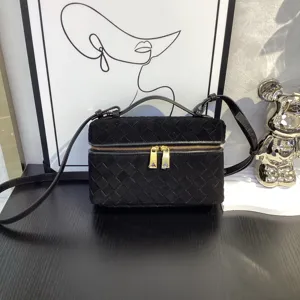 Black suede woven vanity bag detail, featuring top handle and gold zipper for women.
