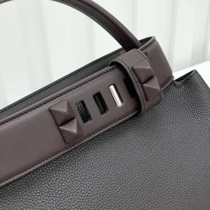 Dark brown leather handbag detail with pyramid studs and metal closure for women.