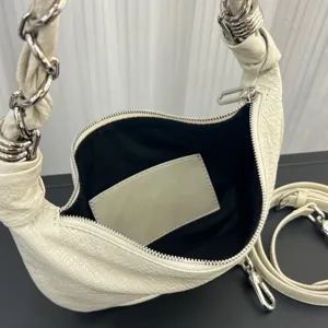 White leather dumpling shoulder bag detail, featuring chain strap, zipper and black lining.