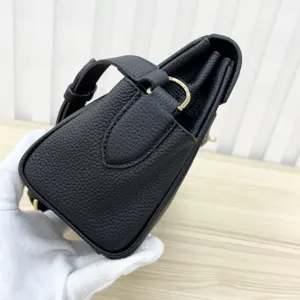 Black leather Kelly style messenger bag side detail showcasing fine craftsmanship and gold hardware.