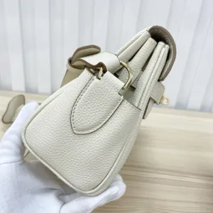 Detail view of genuine leather women handbag side structure with brown trim and gold hardware