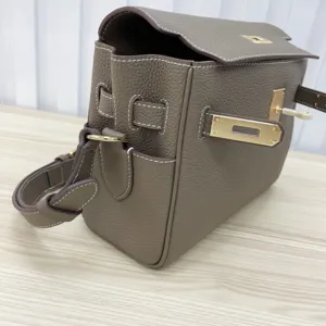 Detailed view of genuine leather women messenger bag with iconic metal lock and shoulder strap.