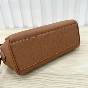Brown leather Kelly bag bottom detail showing fine white stitching and premium textured grain material.