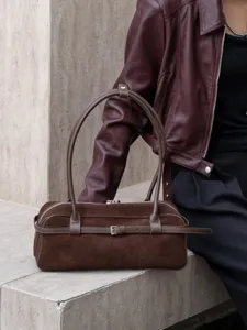Detailed shot of vintage brown suede leather baguette shoulder bag with buckle strap.