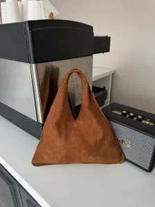 Vue detaillee du sac a main triangulaire en daim marron avec une poignee douce et elegante.