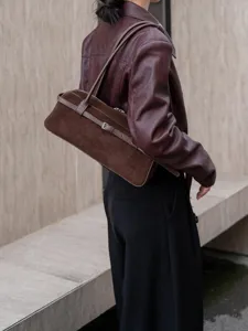 Detail shot of a brown suede leather shoulder bag, vintage east-west tubular design with strap.