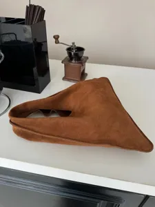 Vue détaillée de sac à main triangle en suédine marron, forme géométrique unique.