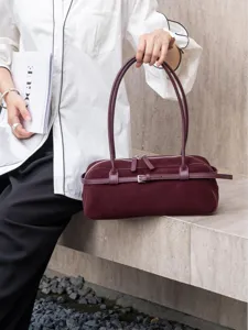 Dark red suede baguette shoulder bag detail showing delicate double straps and buckle design.