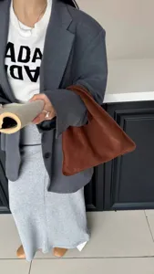 Détail du sac sous les aisselles en daim marron, associé à un blazer gris et pull.