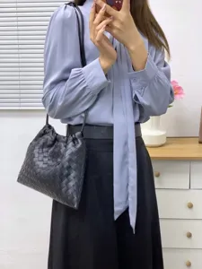 Black woven leather shoulder bag with drawstring closure and stylish design for women.