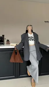 Vue détaillée du sac à main triangle en daim marron vintage associé à un blazer et une jupe.