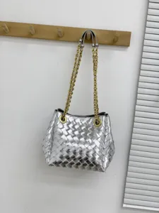 Sac à épaule en cuir tressé argenté avec des lanières de chaîne dorée, style seau élégant.