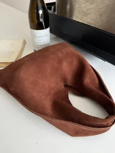 Gros plan sur le sac porté épaule en daim marron avec texture douce et design minimaliste.