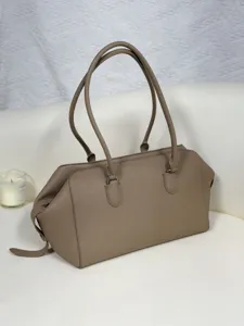Detail view of the taupe genuine leather bowling shoulder bag, minimalist aesthetic.