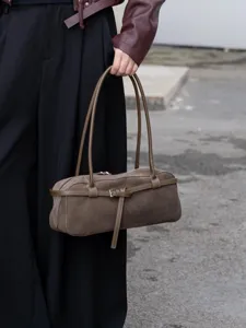 Close-up detail of the retro brown suede baguette shoulder bag with slim straps and chic belt.