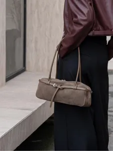 Retro suede leather shoulder bag for women, stylish brown baguette handbag with buckle detail.