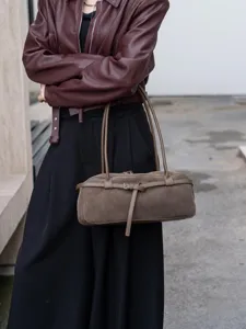 Detailed shot of retro brown suede baguette shoulder bag with stylish decorative strap and buckle.